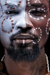 black male with ethnic paintings on face look at camera, confident and powerful. tribal, authentic aborigen people