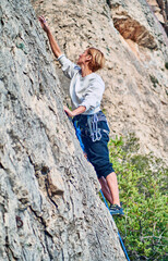 Vertical photo of blonde caucasian girl climbing the mountain