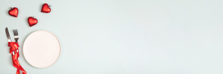 Empty white plate and cutlery. Valentine's Day theme. Place for text.