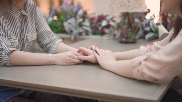 Close up of female hands on a table in a cafe. two young woman are talking while sitting at the table.