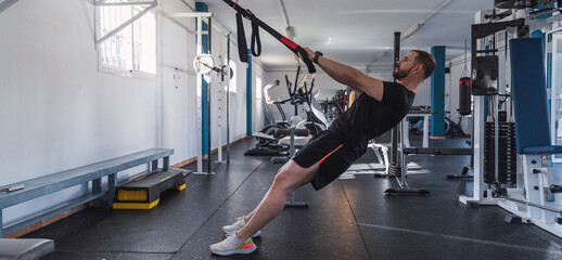 Young man doing TRX exercises at the gym. TRX training. Sport and fitness. Crossfit workout