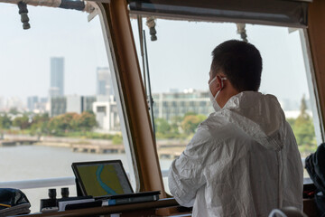Ship pilot on the vessel bridge keeping watch onboard during pilotage.
