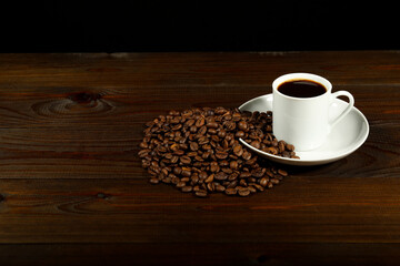 white coffee cup and coffee beans are on a wooden background. cup of aromatic coffee is on a wooden table with copy space
