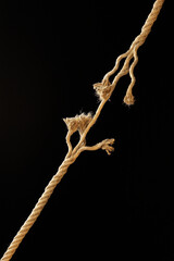 frayed rope that is breaking, isolated on black background