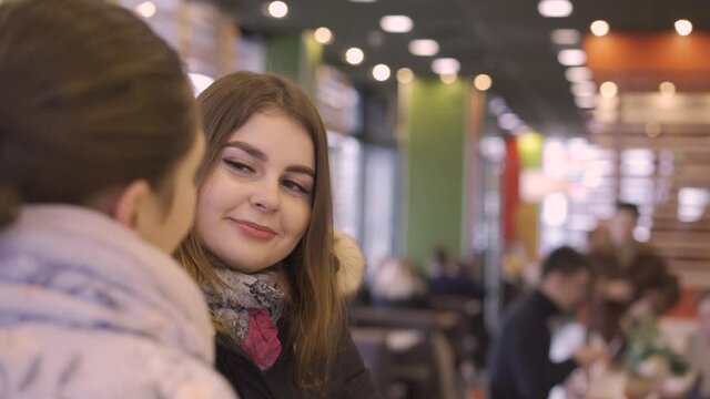 two girls students talk in a fast food cafe and wait for an order