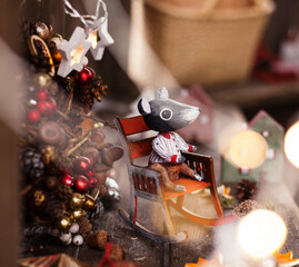 new year and christmas background. wooden toy mouse in rocker and winter wreath behind it.backgrounds for greeting cards