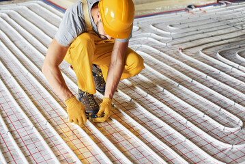 Worker in yellow colored uniform installing underfloor heating system