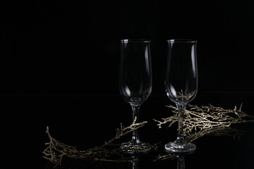 Two empty glasses of champagne and Christmas or New Year decoration on a black background. Romantic dinner. Winter holiday concept.