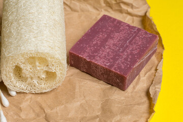 loofah and handmade soap lie on craft paper on a yellow background close-up. place for text. eco...