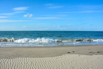 Waves on sand beach with blue sky