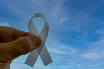 fingers holding white ribbon, representing the mental health prevention campaign. white January.