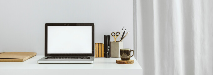 Creative desk with laptop screen, office supplies, brushes, desk objects mug and grey backdrop....