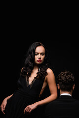 Plakat seductive woman with red lips near man in suit isolated on black