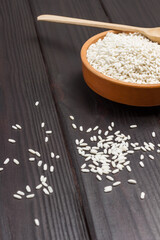 White rice in ceramic bowl. Rice is scattered on table
