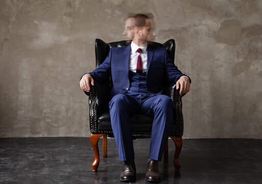 Businessman with split personality sitting in armchair