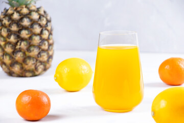 Multifruit juice in glass on white background. Orange juice.Fresh fruits.Healthy food and drink. Limons and tangerines. A pineapple