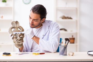 Young male archaeologist studying ancient african stonemask