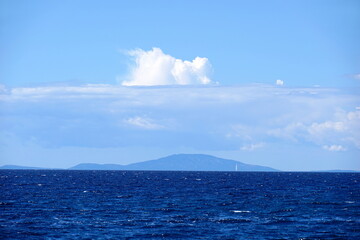 Beautiful view to sea horizon with indigo blue color tone of water and light blue sky with clouds