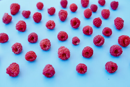 Raspberry pattern, blue background, top view.Pattern of ripe red raspberry on blue background. Vegan food, detox concept