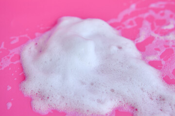 Foam bubbles and brick of soap on pink background. White foam snear from soap, shampoo or cleanser on pink background with selective focus Cleaning service