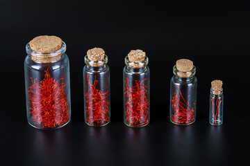 dry spice saffron in a glass bottle on a black background