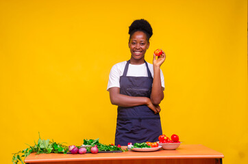 young beautiful african housewife excited as she holds a tomatoes