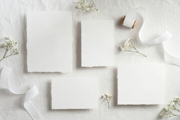 Wedding invitation cards mockups top view. Flat lay blank paper cards, flowers, ribbon on white...