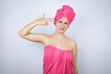 Young beautiful woman wearing shower towel after bath standing over isolated white background Shooting and killing oneself pointing hand and fingers to head like gun, suicide gesture.