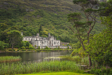 Landscape view of Kylemore Abbey and Green Victorian Walled Garden standing above blue lake. Ireland. Europe