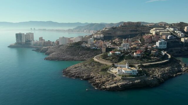 Distant drone point of view Cullera rocky coastline and townscape during sunny winter day. Touristic spanish famous place. Province of Alicante, Costa Blanca, Spain