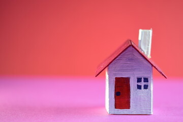 Miniature house on pink and red background using as property real estate and family concept. Saving for future life. 