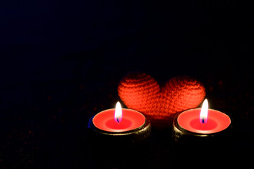 Burning light candles and blurred red heart on black background. Holiday special and valentine...