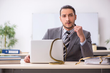 Young male employee with snake in the office