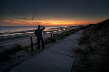 man looking at the sunset on the beach
