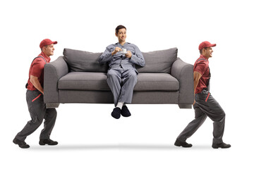 Movers carrying a sofa with a man in pajamas sitting and drinking coffee