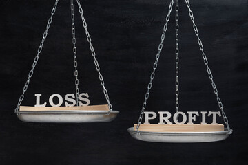 Balance LOSS and PROFIT. Scales on black background close up