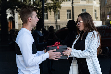 Guy gives the surprised girl gift. Happy birthday valentine day.