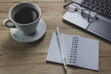 Conceptual workspace wood texture background,  laptop, keyboard, cup of coffee and notes bloc, background