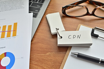 There is a piece of paper with a graph printed on it, a clipboard, and an open vocabulary book on the desk. The word CDN is there. It's an acronym that means Content Delivery Network.