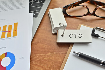 There is a piece of paper with a graph printed on it, a clipboard, and an open vocabulary book on the desk. The word CTO is there. It's an acronym that means chief technical officer.