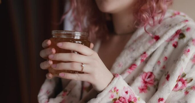 Woman sniff a jar of honey at home