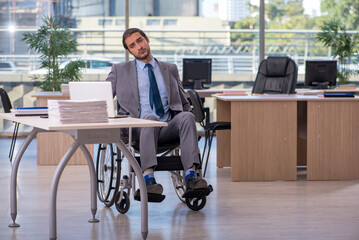 Young male employee in wheel-chair working in the office