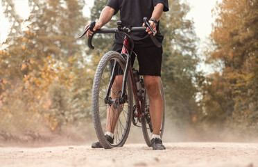 Cyclist with a gravel bicycle on a dusty country road. Active lifestyle concept.