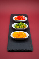 three small try-plates with green, yellow and red peppers on slate plate
