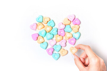 The heart is lined with pieces of figured sugar on a white background. The girl is holding sugar. Love symbol for valentine's day