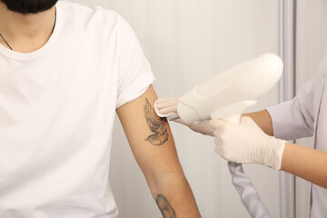 Fototapeta premium Young man undergoing laser tattoo removal procedure in salon, closeup