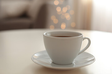 Cup of aromatic coffee on table indoors. Bokeh effect
