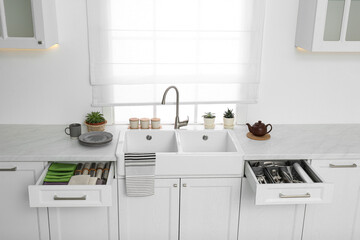 Open drawers with different utensils, towels and napkins in kitchen