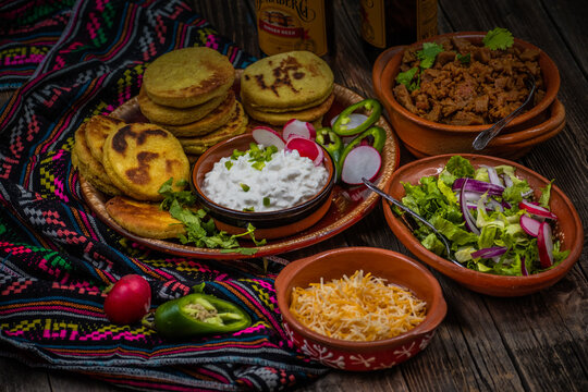 Traditional mexican gorditas with various vegetarian and vegan fillings: seitan, greens, cheese on wooden table