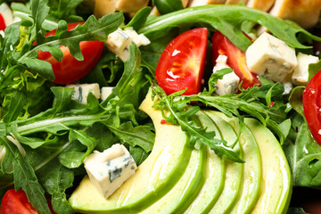 Delicious salad with arugula, tomatoes and avocado as background, top view